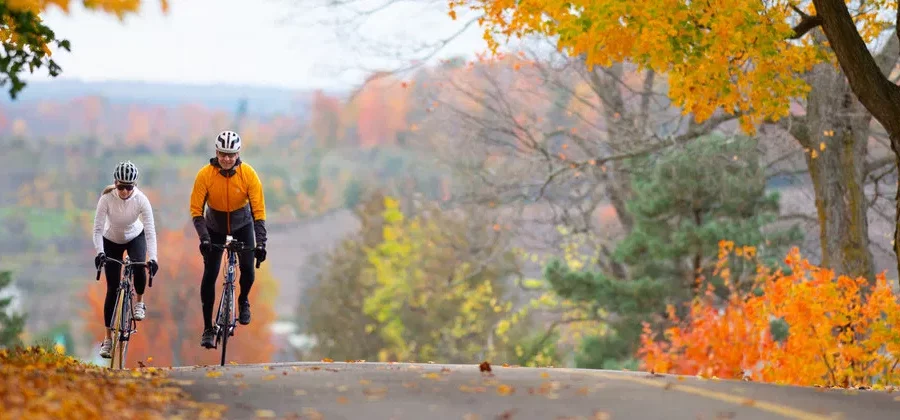 Deux personnes faisant du vélo sur la route dans les Laurentides en automne